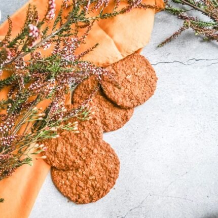 Top view of oatmeal cookies on a rustic surface with floral accents, perfect for food photography.