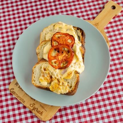 Savory open-faced sandwich with scrambled eggs and tomatoes on bread, perfect for a hearty breakfast.