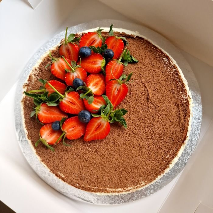 pexels-photo-16461655-16461655-1 Top view of a tiramisu cake decorated with fresh strawberries and blueberries, perfect for dessert lovers.