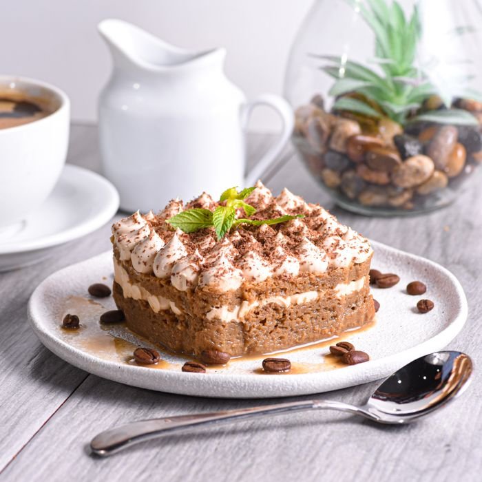 pexels-photo-17558644-17558644 Tiramisu cake with cream topping, garnished with mint and coffee beans.