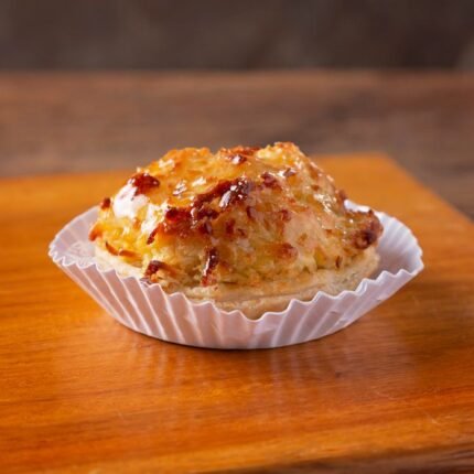 Close-up of a glazed coconut macaroon on a wooden table, perfect for dessert lovers.
