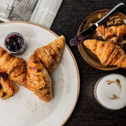 Tasty croissants with jam and cappuccino, perfect for a cozy breakfast.