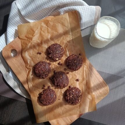 A tempting display of chocolate chip cookies on a wooden board accompanied by a glass of milk. Perfect for snack time.