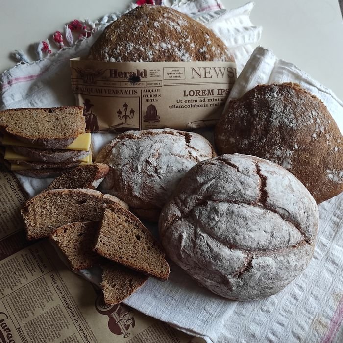 Assorted loaves and slices of artisan bread on a table with vintage newspaper.