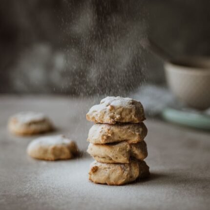 Stack of delicious homemade cookies with powdered sugar, perfect for snacking and baking inspiration.