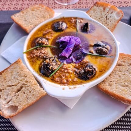 Delicious gourmet dish of escargot with a vibrant edible flower garnish, perfect for upscale dining.
