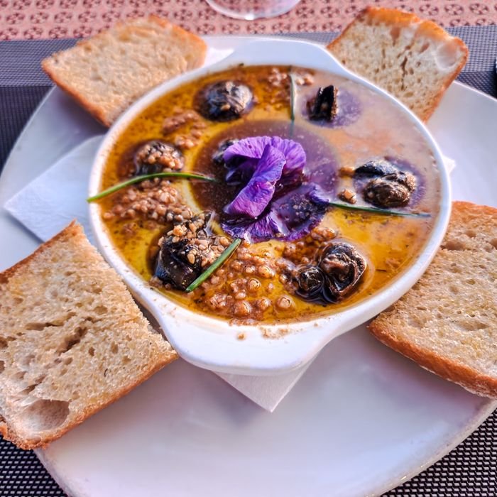 Delicious gourmet dish of escargot with a vibrant edible flower garnish, perfect for upscale dining.
