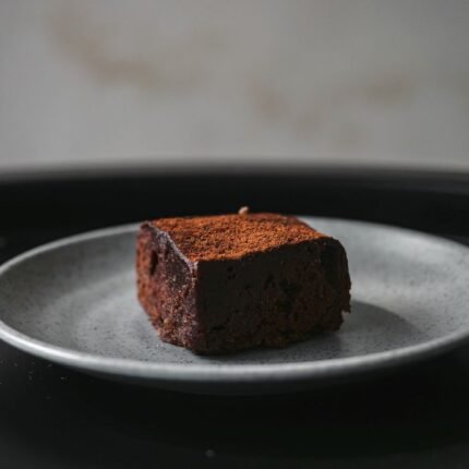 Close-up of a decadent chocolate brownie on a speckled gray plate.