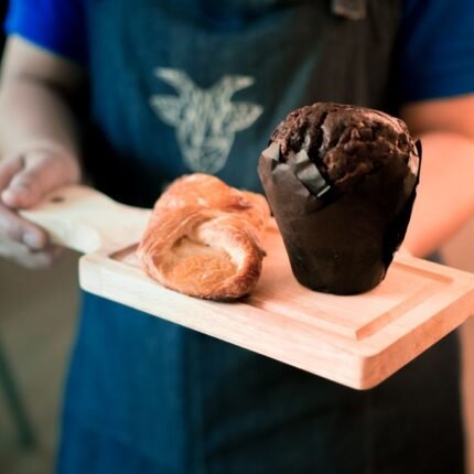 Indulge in a tasty chocolate muffin and flaky croissant served on a rustic wooden board.