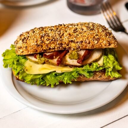 Delicious chicken sandwich with cheese, lettuce, avocado, and multigrain bread for a healthy meal.