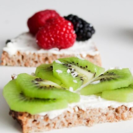 Close-up of wholesome fruit-topped toast featuring fresh kiwi and berries, perfect for a nutritious breakfast.