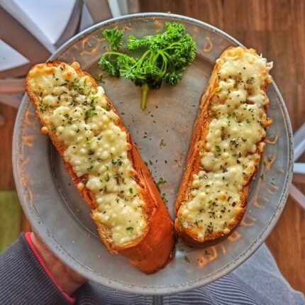 Appetizing garlic bread with melted cheese on a ceramic plate, garnished with parsley, in a still life setting.